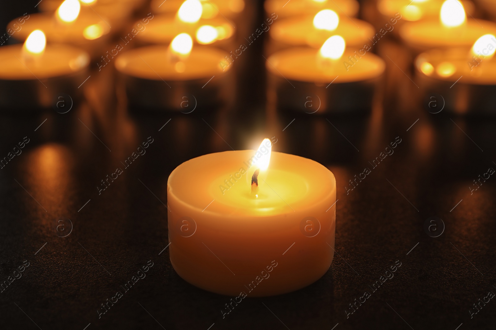 Photo of Wax candle burning on table in darkness, closeup