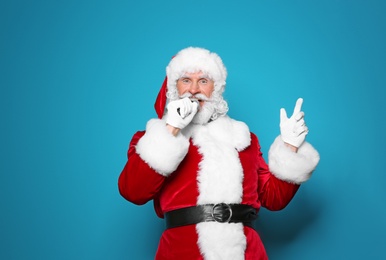 Photo of Santa Claus singing into microphone on color background. Christmas music