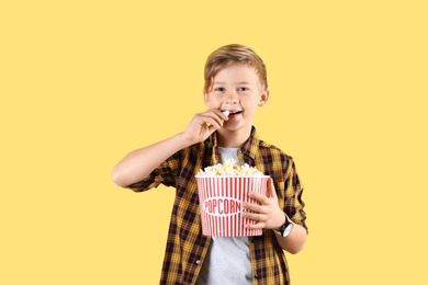 Photo of Cute boy with popcorn bucket on color background