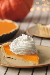 Piece of fresh homemade pumpkin pie with whipped cream on table