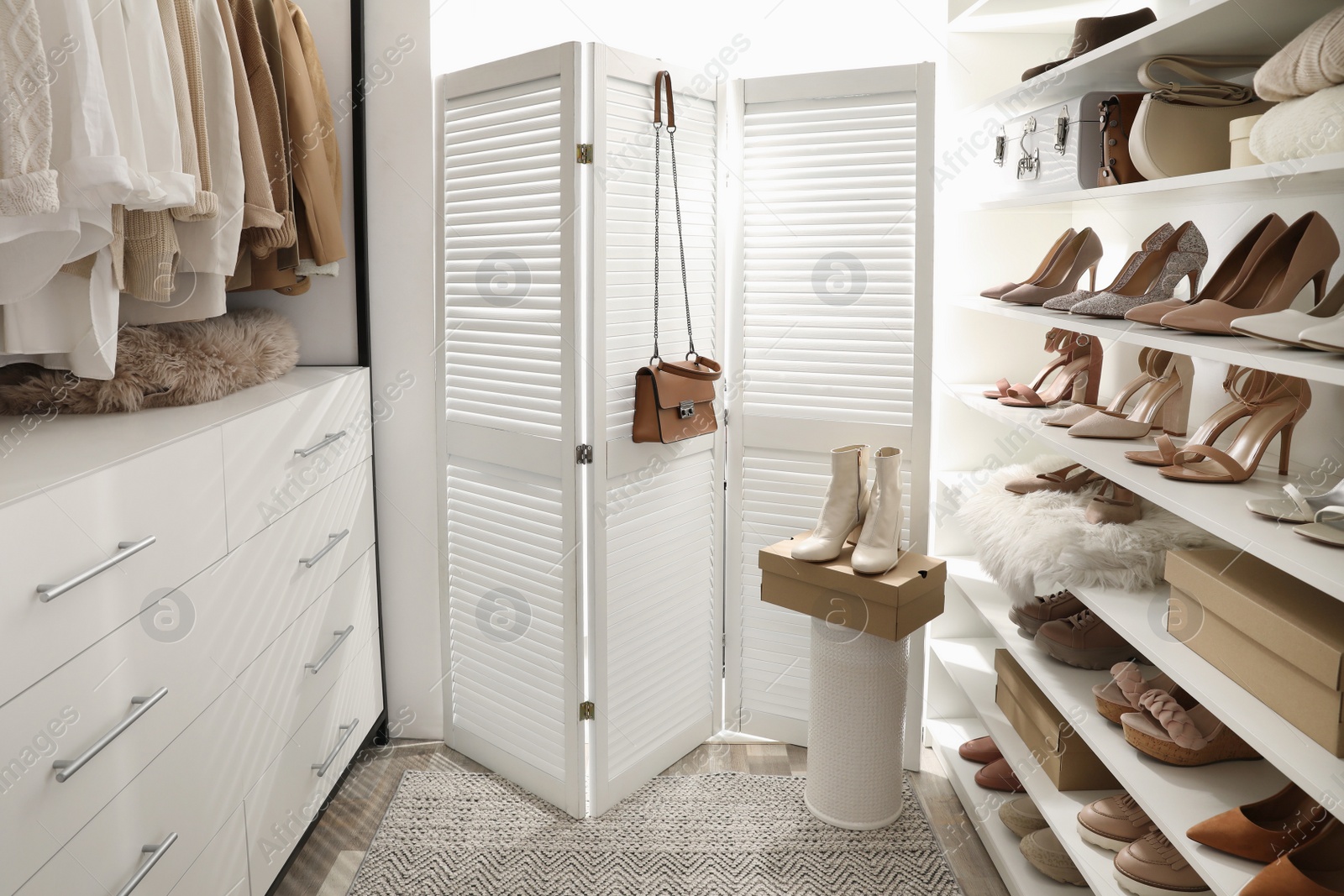 Photo of Dressing room interior with clothes rack and collection of stylish shoes
