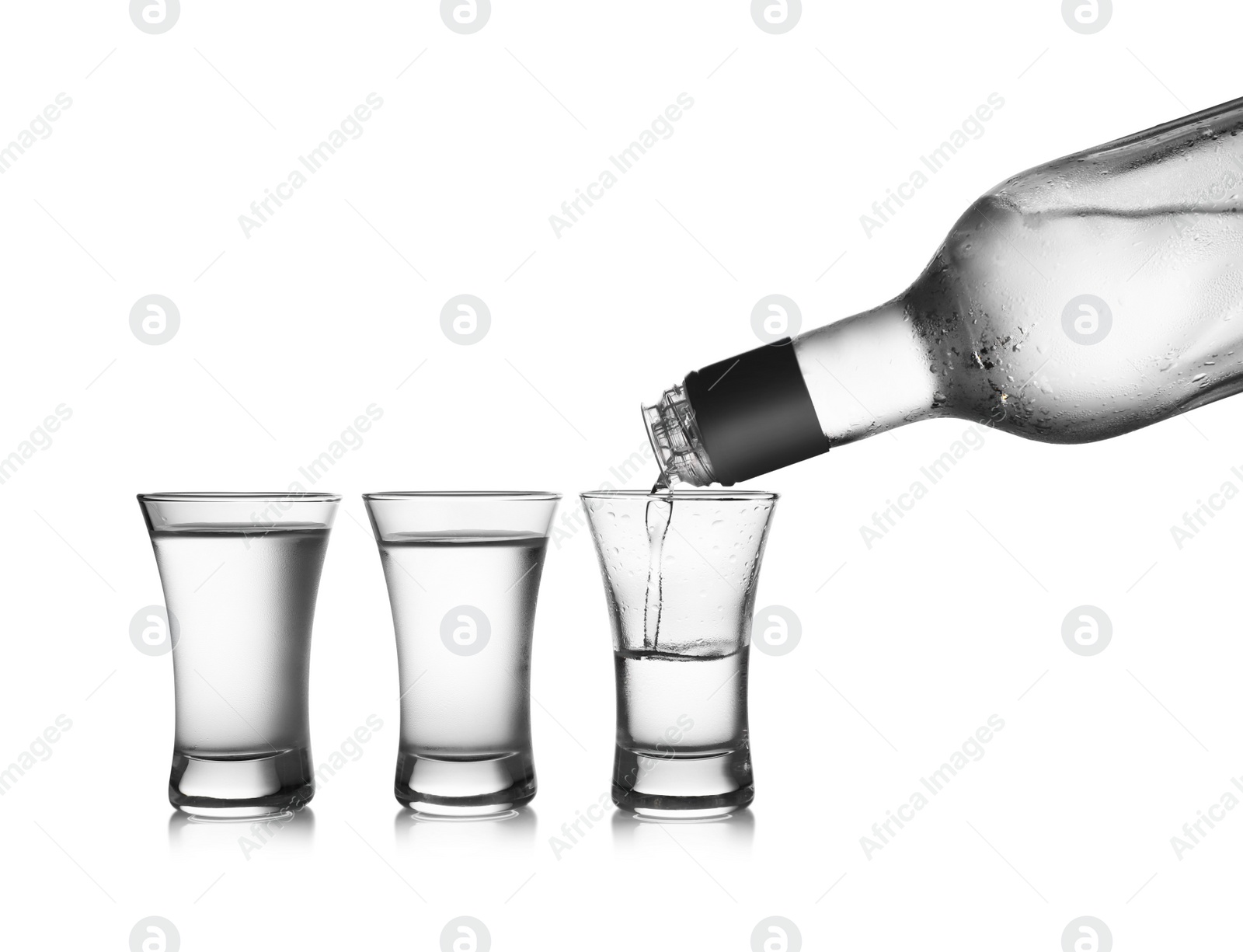 Photo of Pouring cold vodka into shot glass on white background