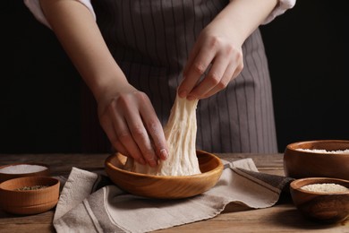 Woman making grissini at wooden table, closeup