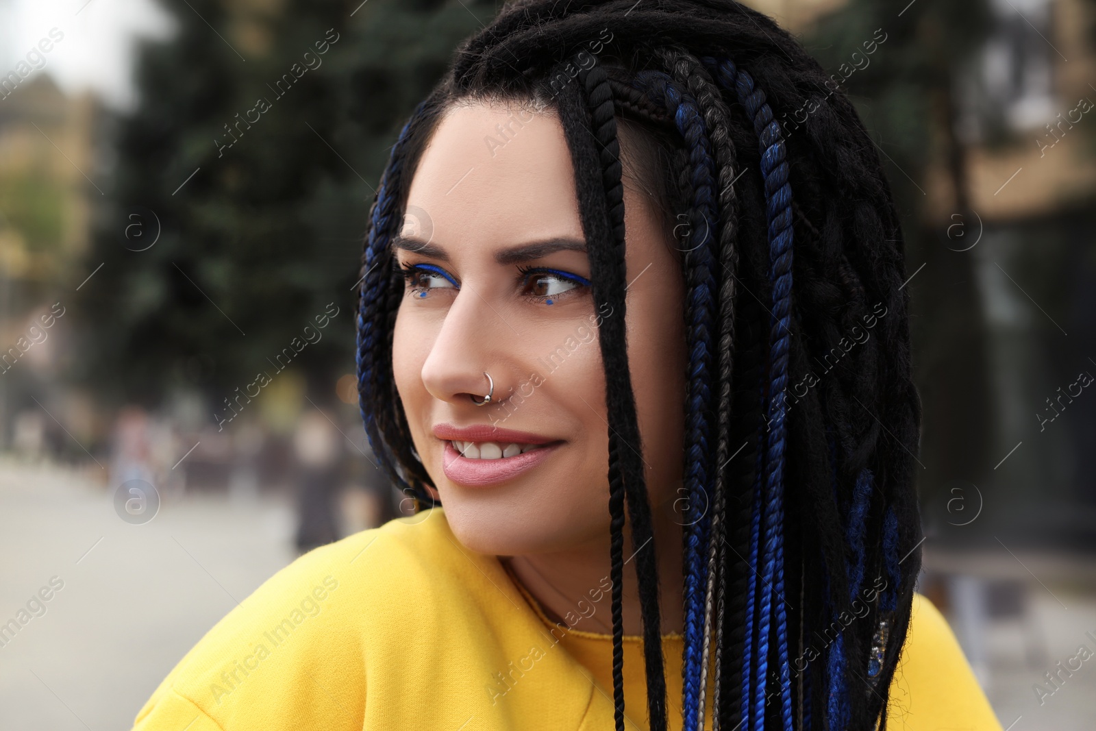 Photo of Beautiful young woman with nose piercing and dreadlocks outdoors
