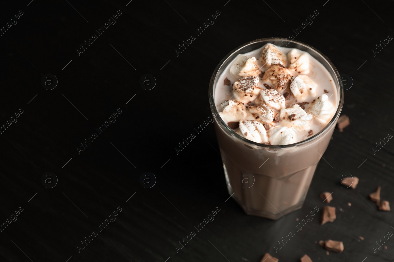 Photo of Tasty hot chocolate with milk and marshmallows in glass on table. Space for text