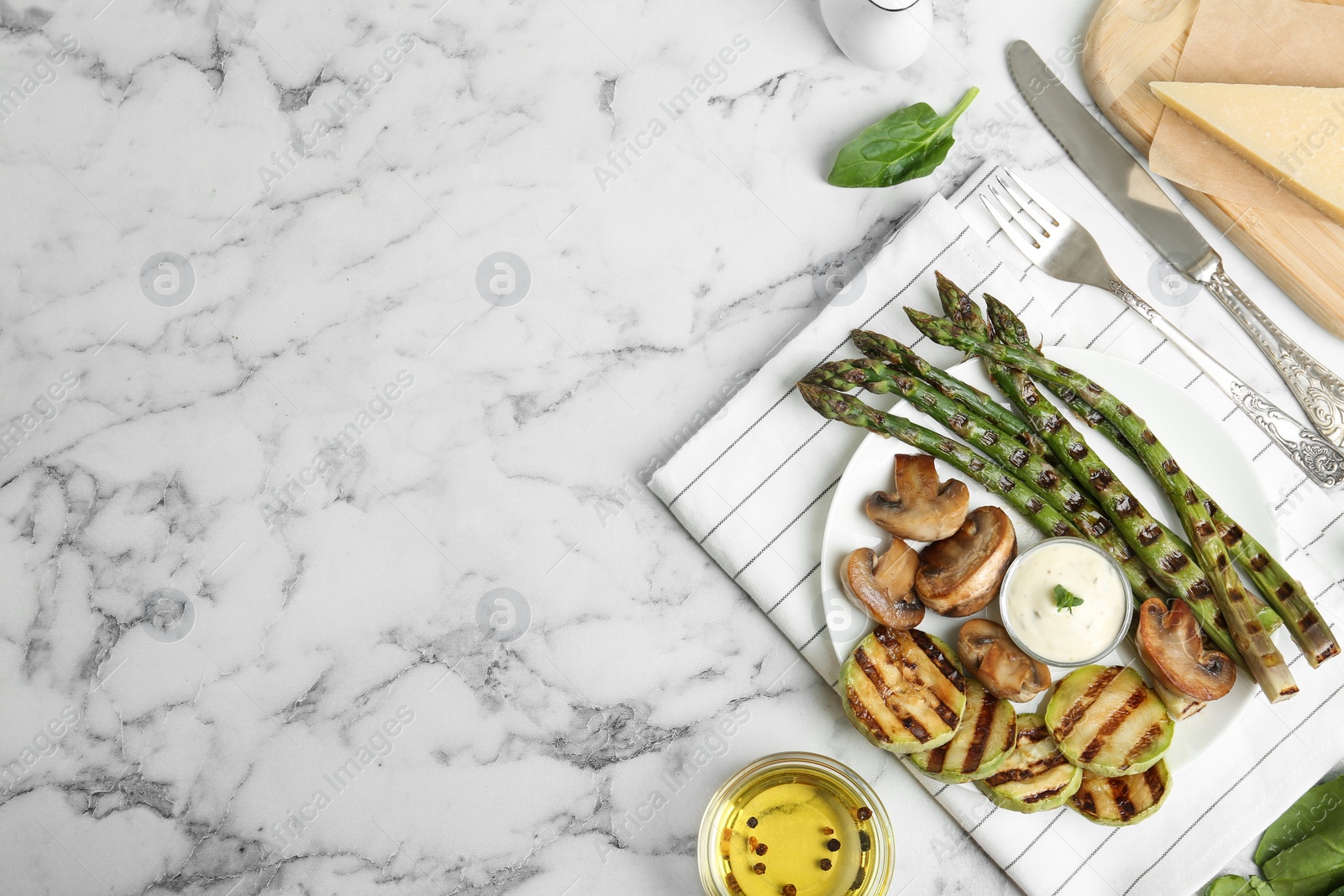 Photo of Tasty grilled asparagus served with sauce, zucchini and mushrooms on white marble table, flat lay. Space for text