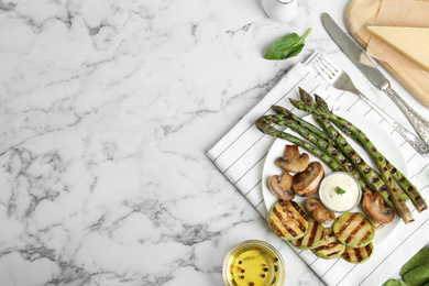 Tasty grilled asparagus served with sauce, zucchini and mushrooms on white marble table, flat lay. Space for text