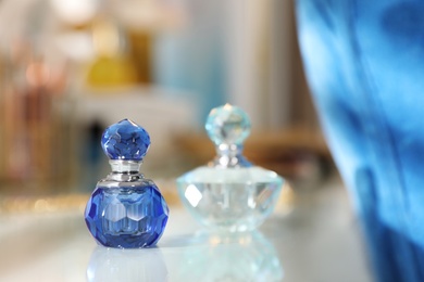 Photo of Bottles of perfumes on dressing table in stylish room interior