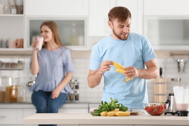 Young couple preparing delicious milk shake in kitchen