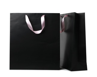 Paper shopping bags with ribbon handles on white background. Mockup for design