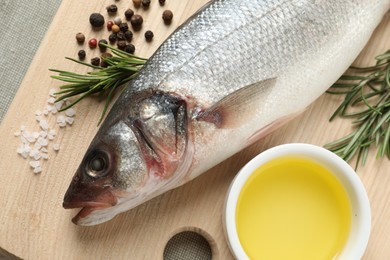 Tasty sea bass fish and spices on wooden board, top view