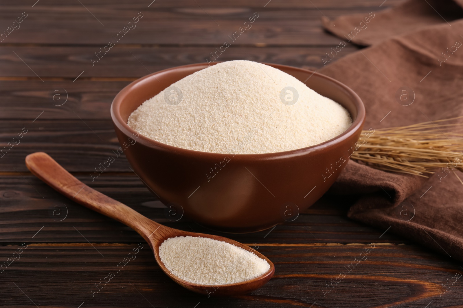 Photo of Uncooked organic semolina and spikelets on wooden table