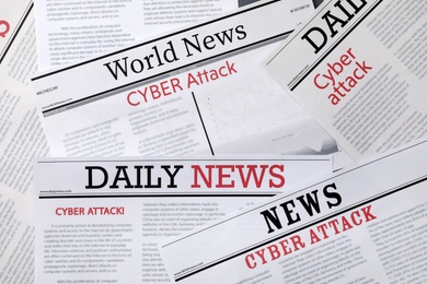 Newspapers with headlines Cyber Attack as background, closeup