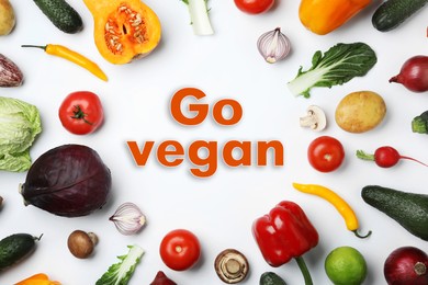 Phrase Go Vegan and fresh vegetables on white background, flat lay