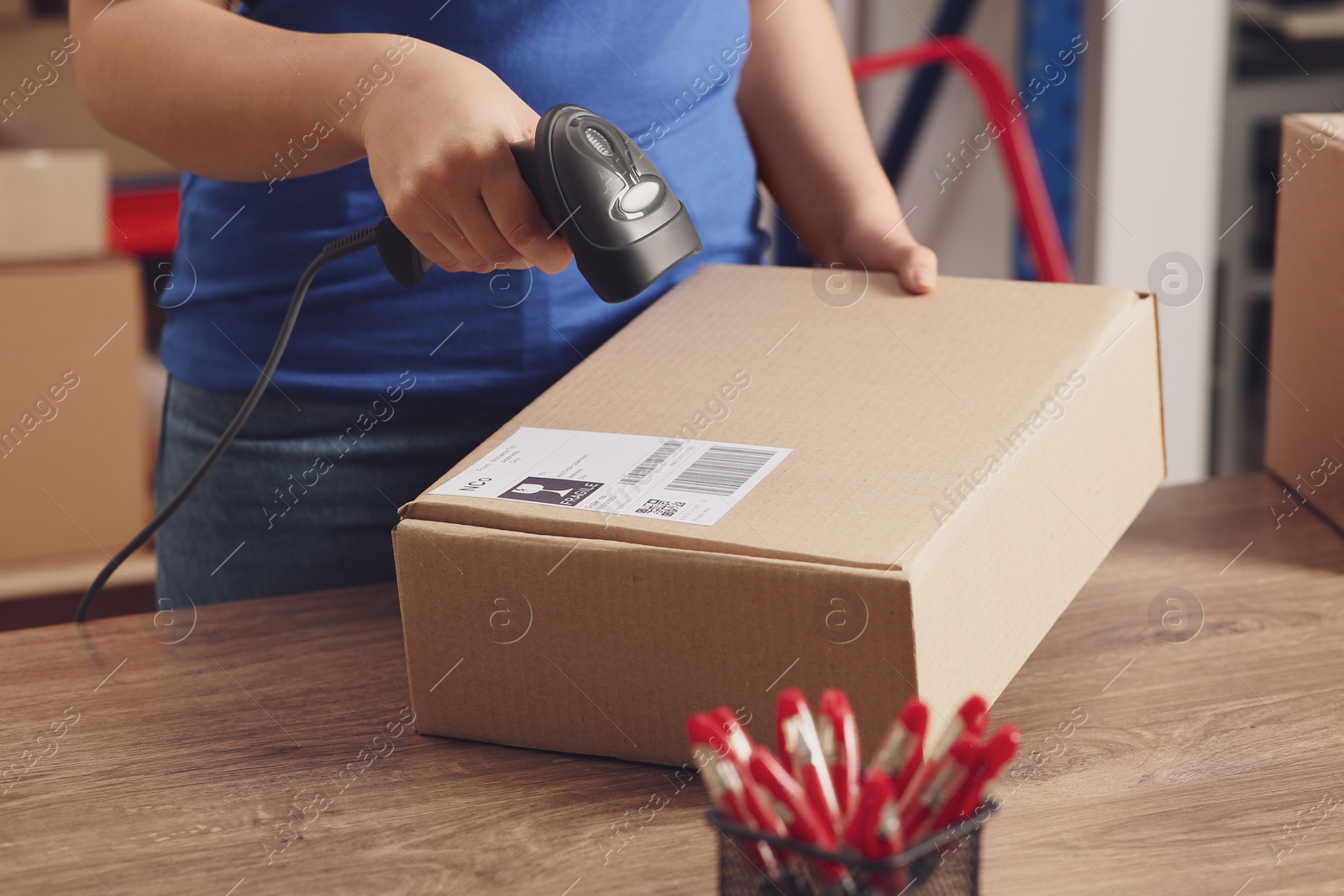 Photo of Post office worker with scanner reading parcel barcode at counter, closeup