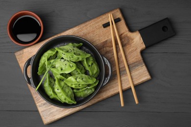 Delicious green dumplings (gyozas) served on grey wooden table, flat lay