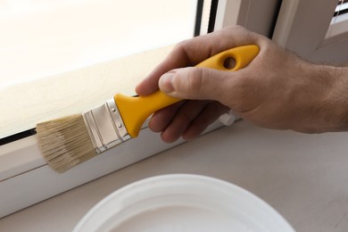 Photo of Man painting window frame at home, closeup