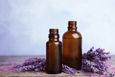 Photo of Bottles with aromatic lavender oil on wooden table