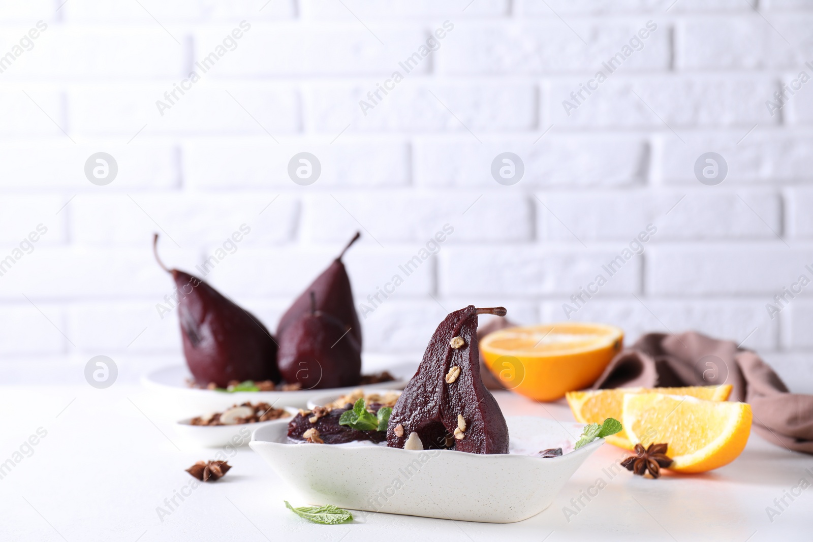 Photo of Tasty red wine poached pears with muesli in bowl on white table