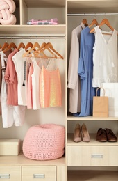 Photo of Stylish clothes, shoes and home stuff in wardrobe closet