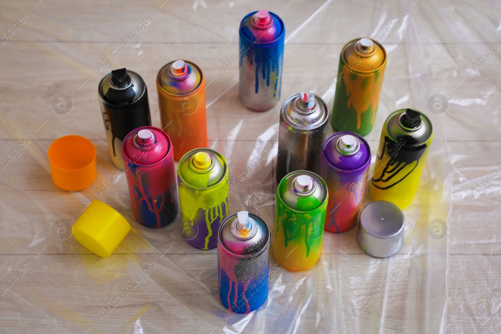 Photo of Used cans of spray paints on floor indoors. Graffiti supplies
