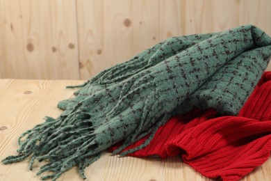 Photo of Soft green and red scarfs on wooden table