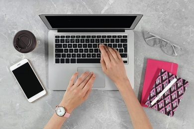 Woman using modern laptop at marble table, top view