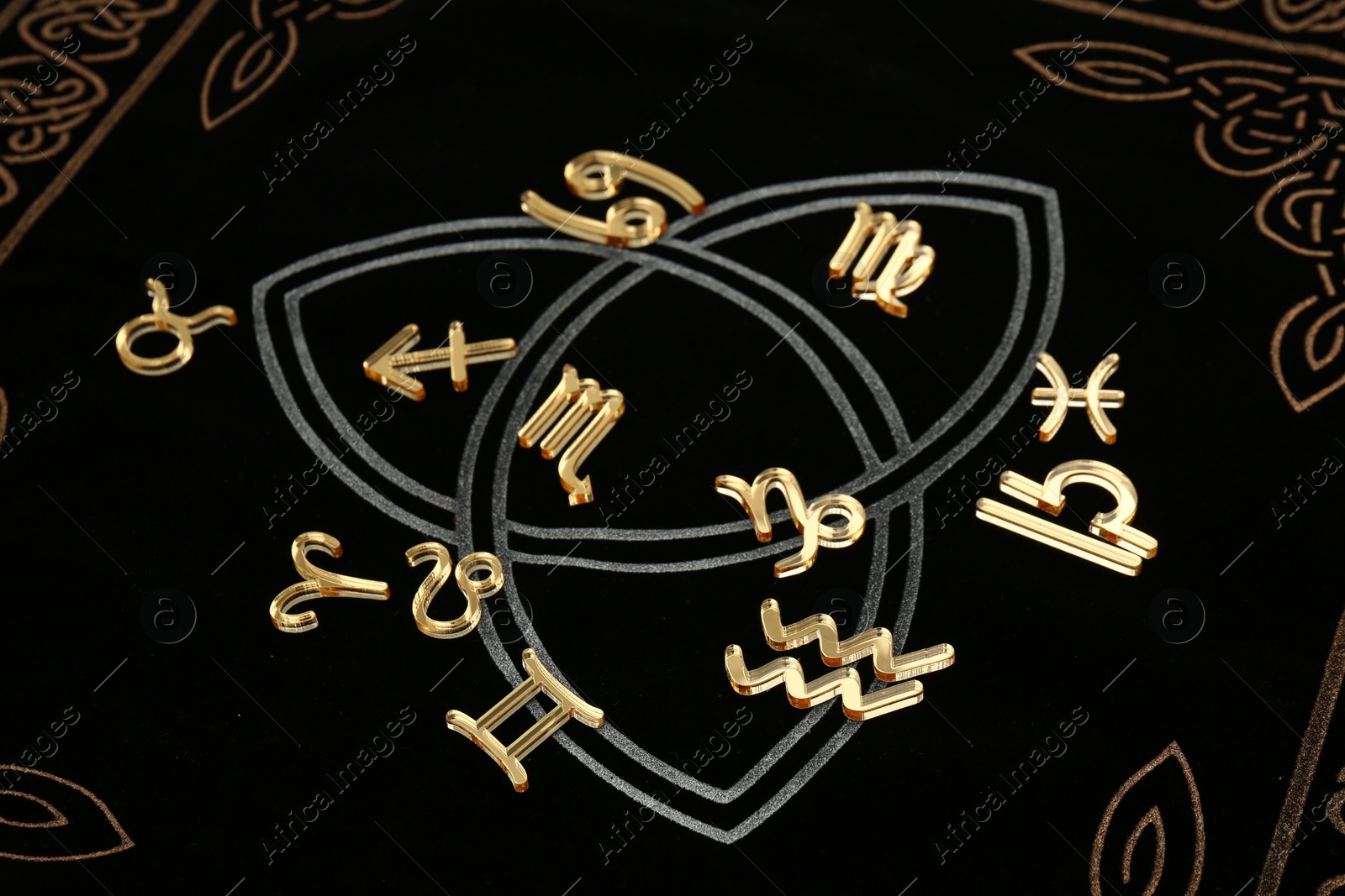 Photo of Many golden zodiac signs on dark book