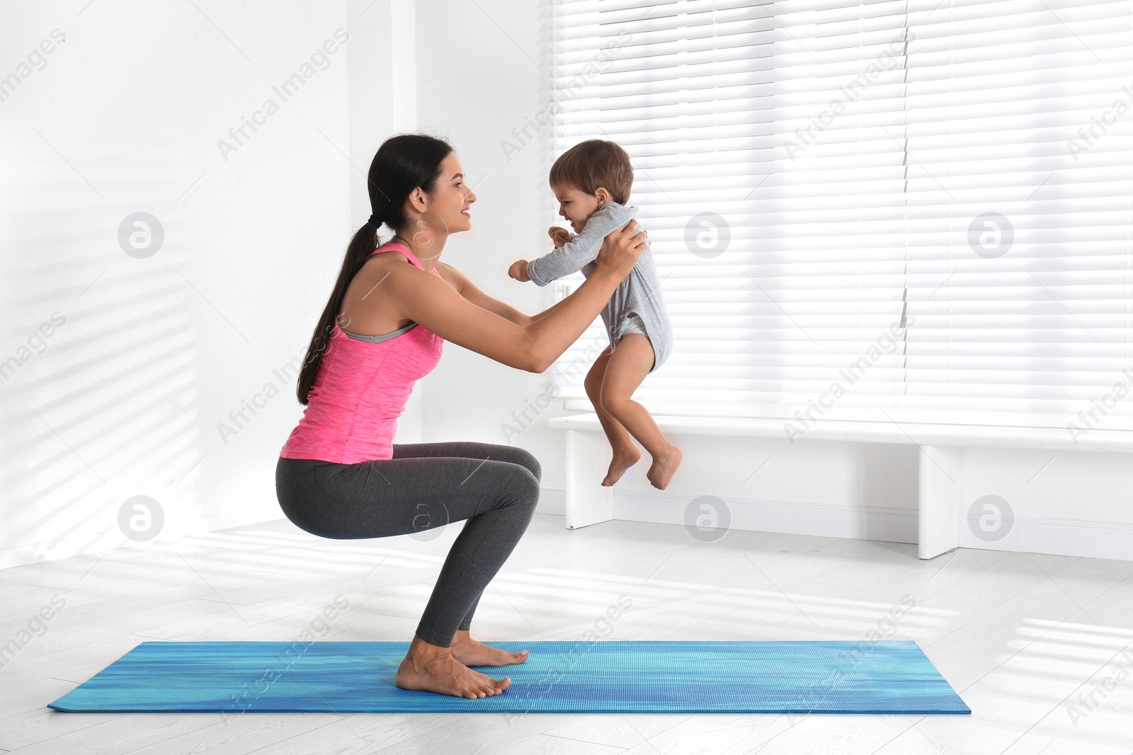 Photo of Young woman doing exercise with her son indoors. Home fitness