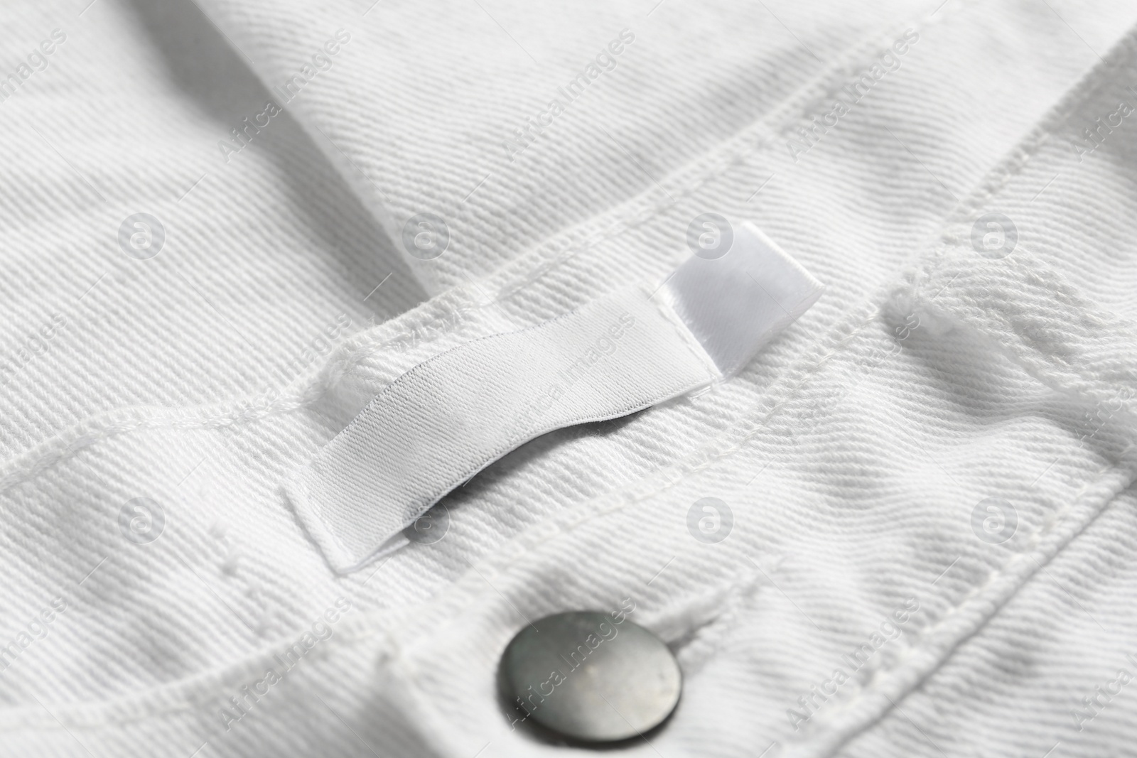 Photo of Blank clothing label on white jeans, closeup