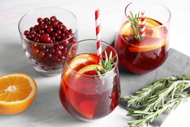 Photo of Tasty refreshing cranberry cocktail with rosemary on table