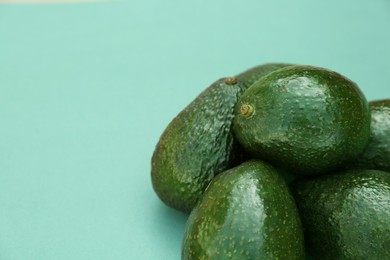 Photo of Many tasty ripe avocados on turquoise background. Space for text