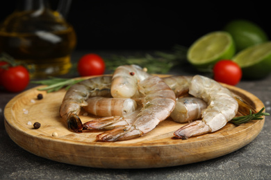 Photo of Fresh raw shrimps with rosemary on wooden board