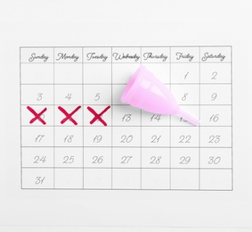 Calendar and menstrual cup on white background, top view. Gynecological care