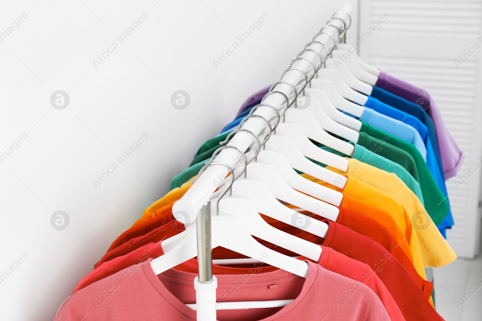 Photo of Rack with bright clothes on light background