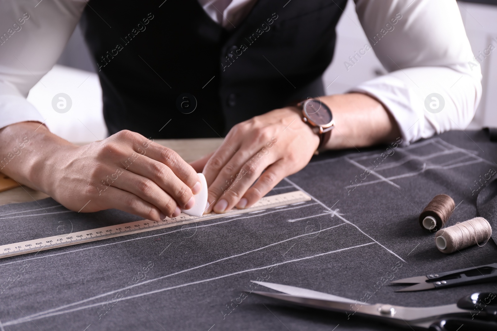 Photo of Tailor working at table in atelier, closeup