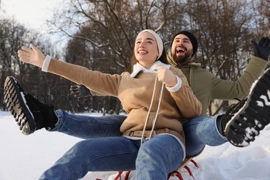 Photo of Happy young couple sledding outdoors on winter day