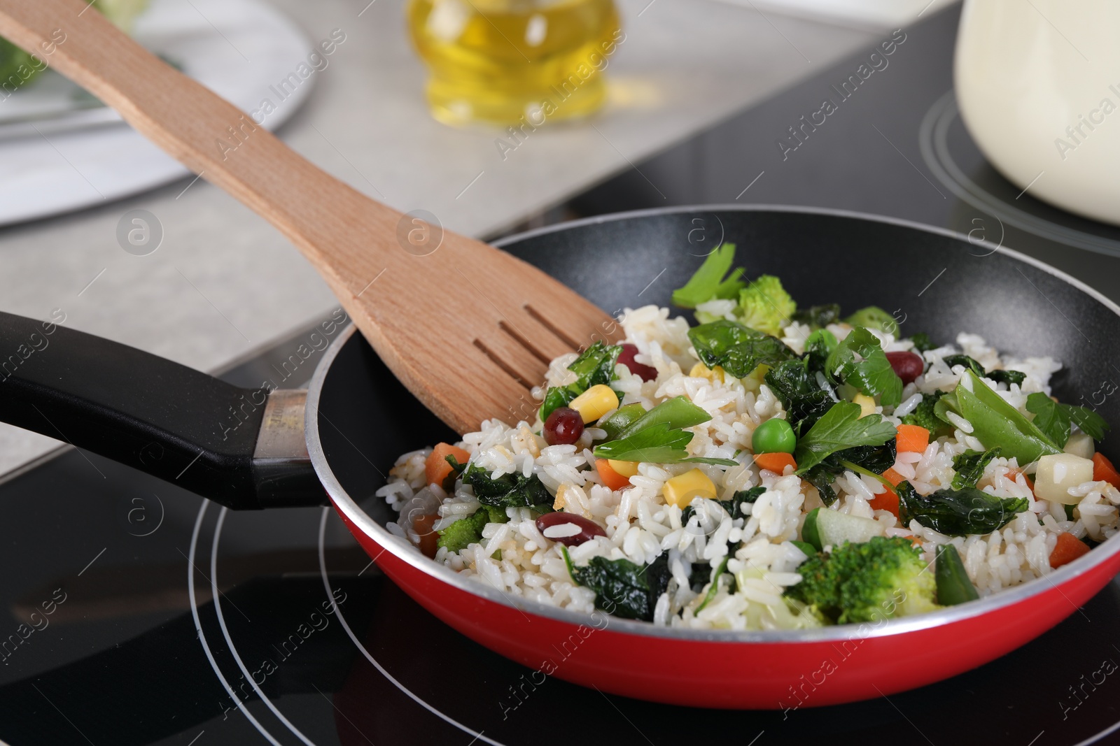 Photo of Frying tasty rice with vegetables on induction stove in kitchen, closeup