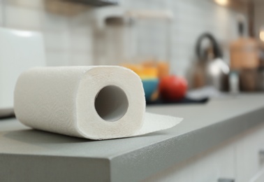 Roll of paper towels on table in kitchen, space for text