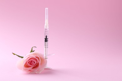 Photo of Cosmetology. Medical syringe and rose flower on pink background, space for text