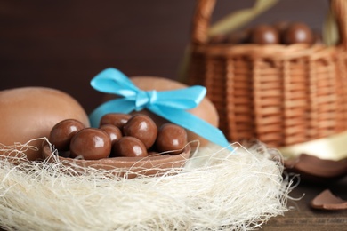 Photo of Tasty chocolate eggs with candies in decorative nest, closeup