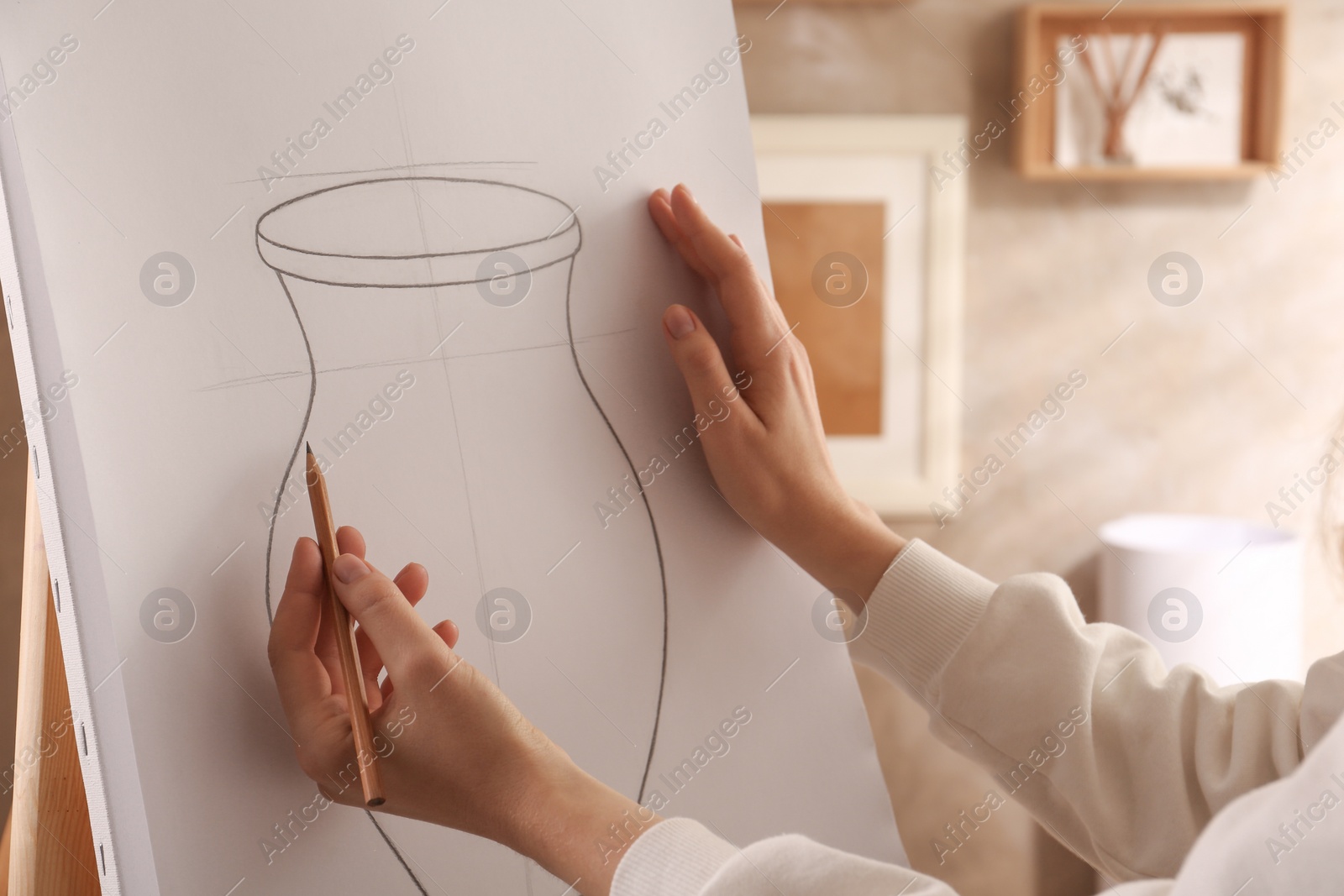 Photo of Woman drawing vase with graphite pencil on canvas indoors, closeup