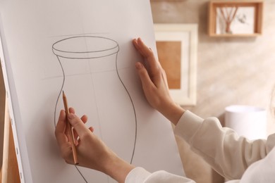 Woman drawing vase with graphite pencil on canvas indoors, closeup