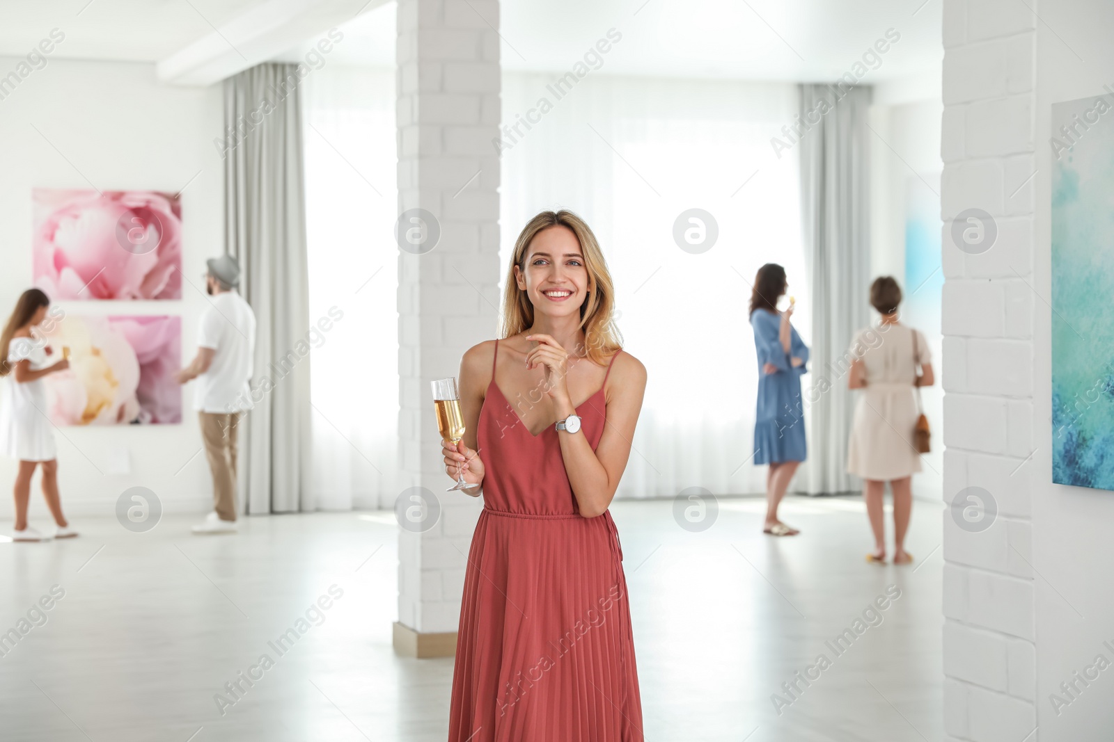 Photo of Young woman with glass of champagne at exhibition in art gallery