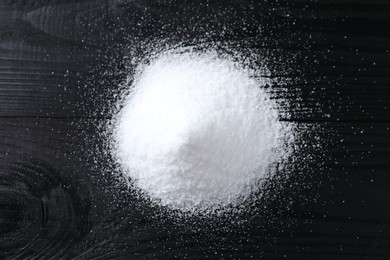 Photo of Pile of organic salt on black wooden table, top view