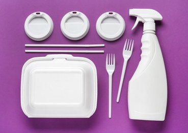 Plastic dishware and sprayer on purple background, flat lay