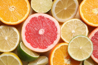 Different cut citrus fruits on beige table, flat lay