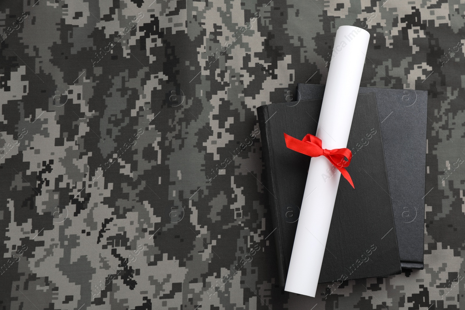 Photo of Books and diploma on camouflage background, top view with space for text. Military education concept