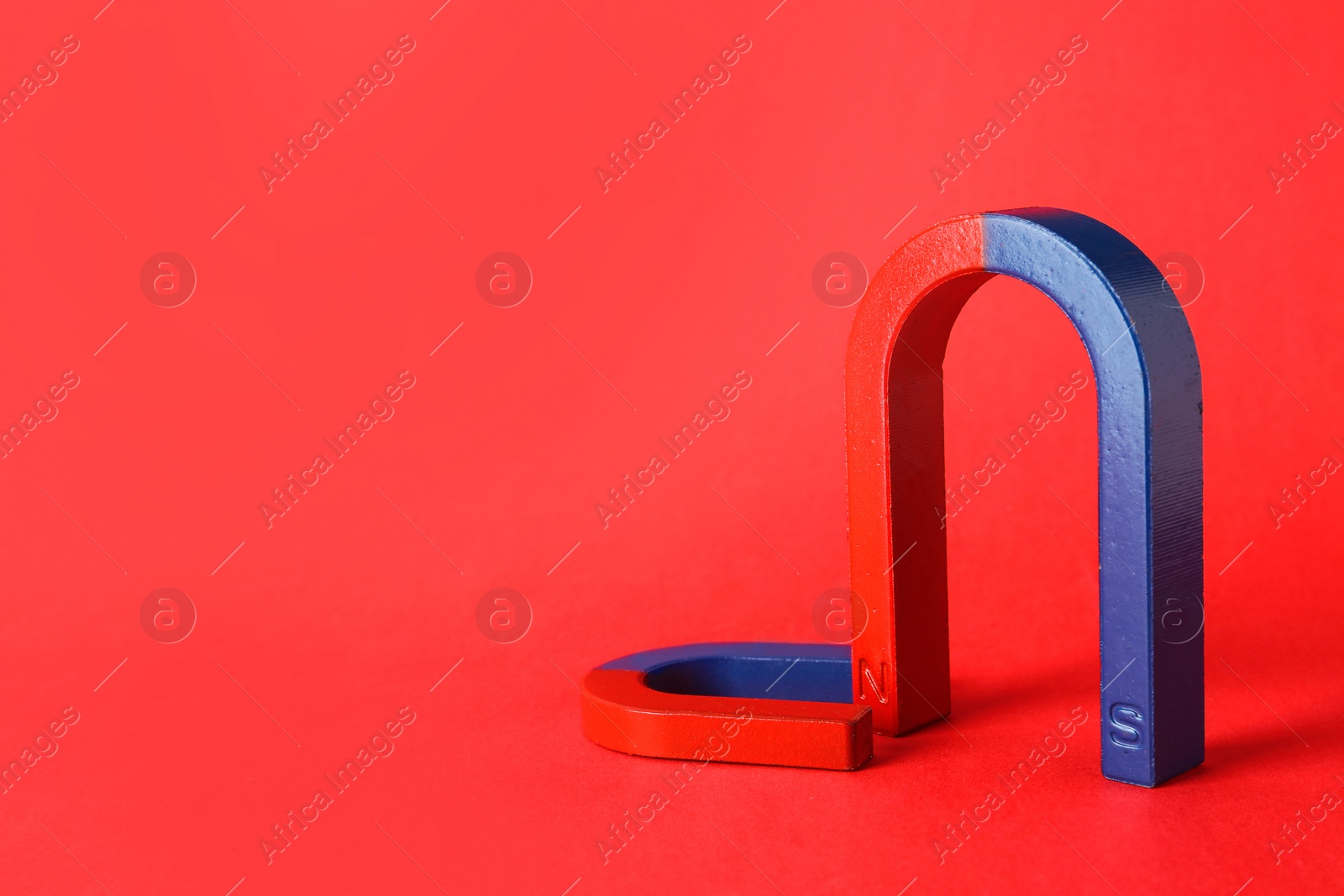 Photo of Red and blue horseshoe magnets on color background. Space for text