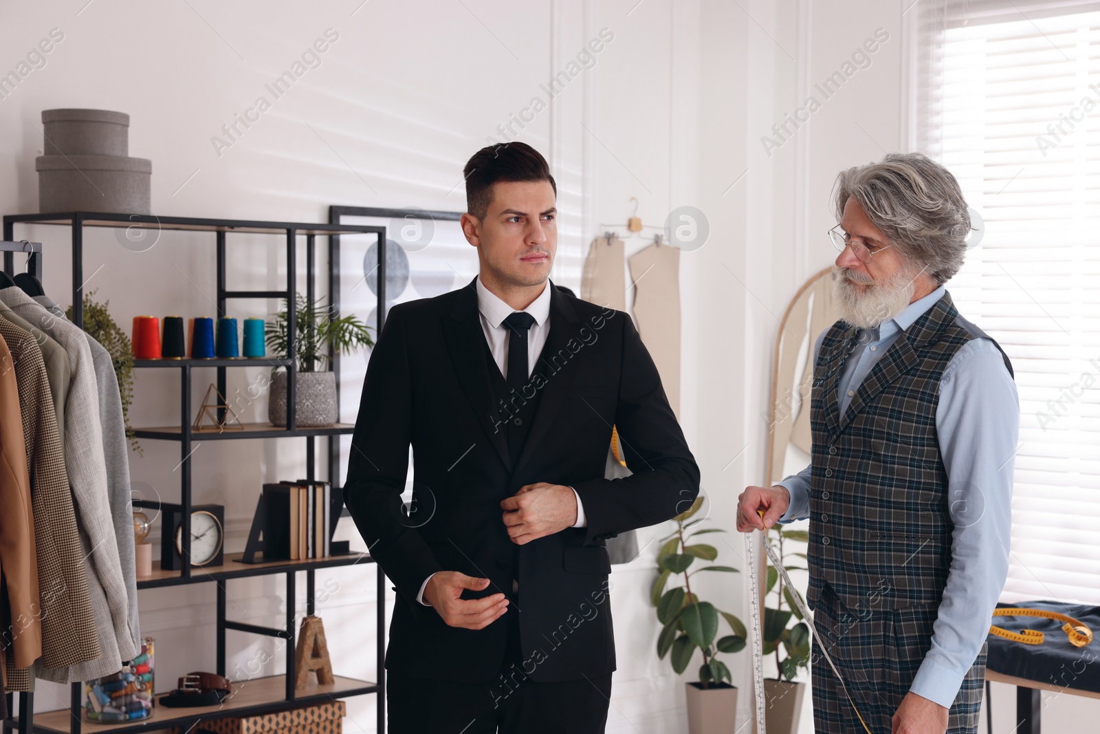 Photo of Professional tailor working with client in atelier